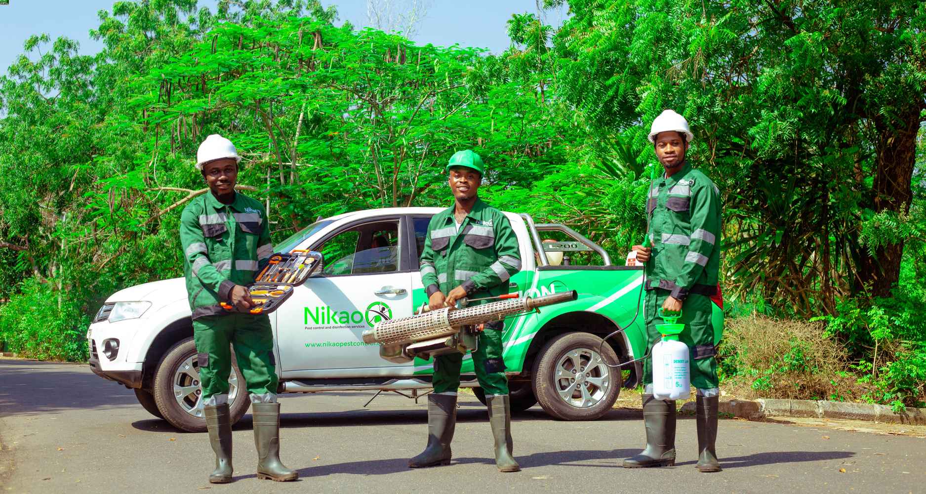 Three Nikao pest control technicians standing with equipment in front of the company pickup truck